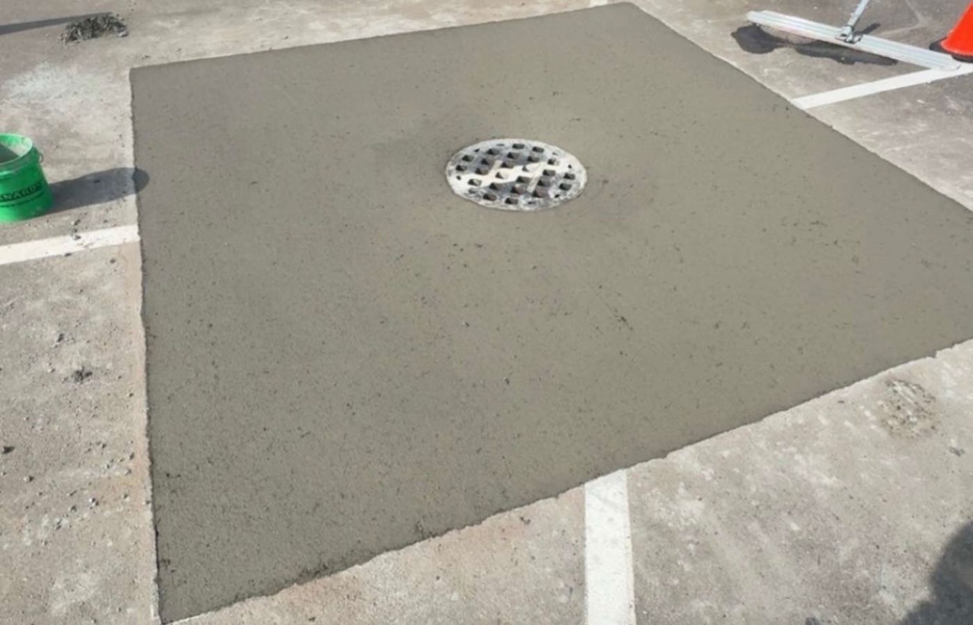 Rebuilt concrete collar around a catch basin in a striped lot