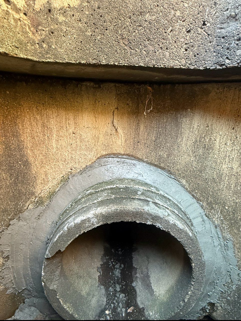 Inside a catch basin, the pipe penetration re-mortared and sealed where it enters the structure