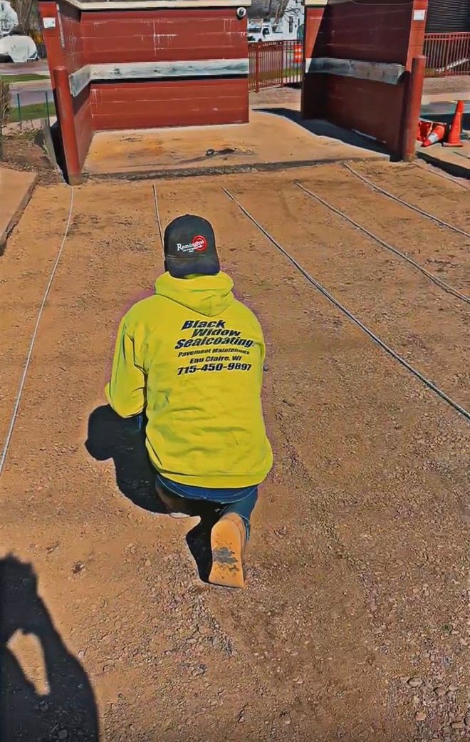 A Black Widow crew member kneeling on a graded base between string lines at a loading dock, setting out before a pour