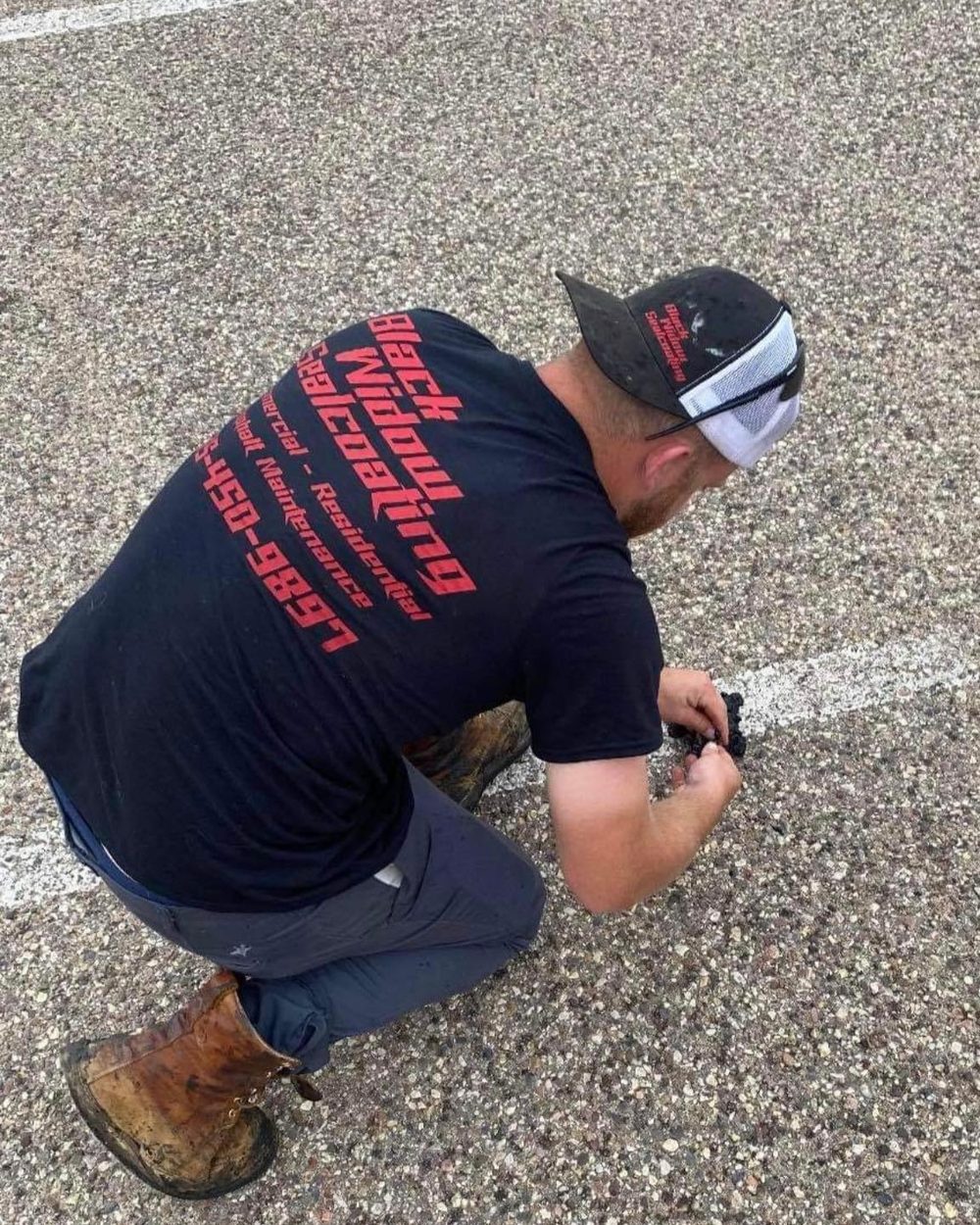 A crew member kneeling at a stall line working patch material by hand