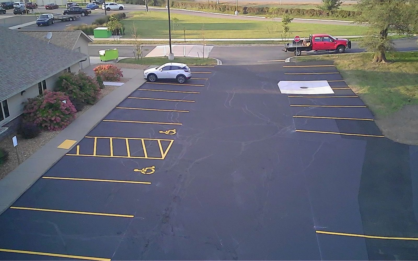 Overhead view of a freshly sealed lot with new yellow stripes and ADA stalls
