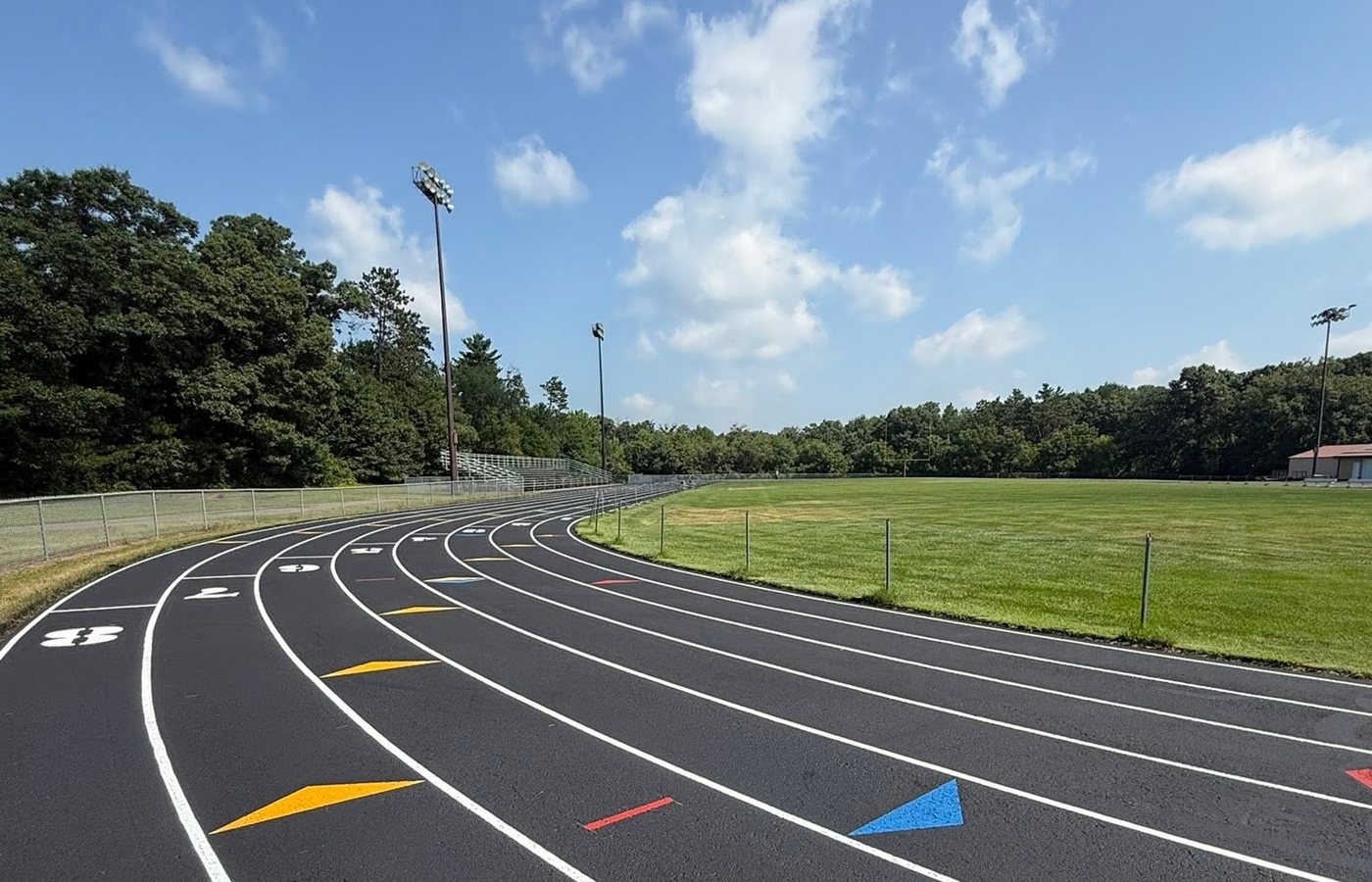A resurfaced running track curve with white lane lines and colored relay exchange zone markers
